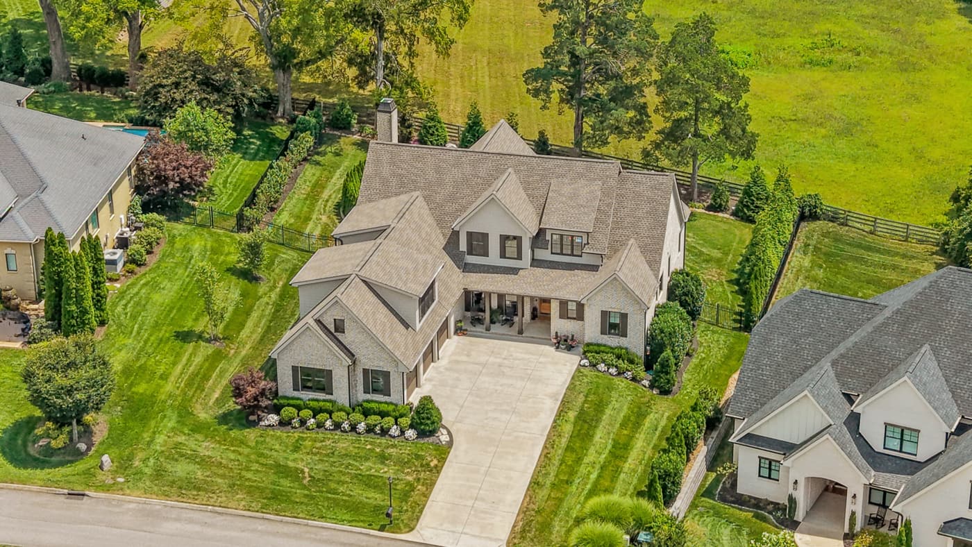 Aerial drone photo of a custom estate home on a landscaped lot