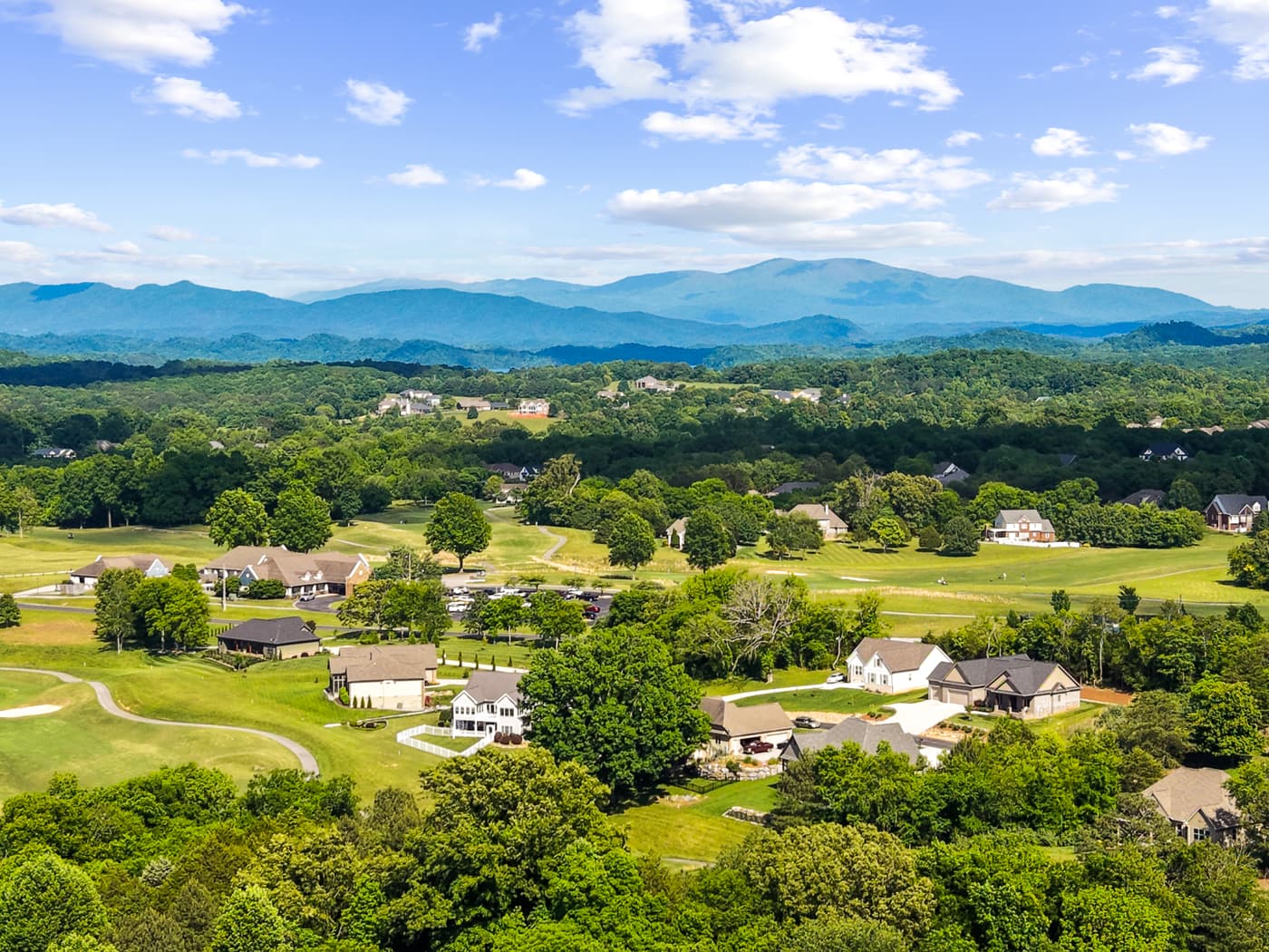 Aerial drone photo of a golf-course community with mountains behind