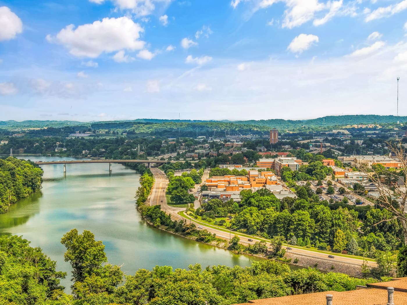 High-altitude drone photo over a river bend with a city bridge in the distance