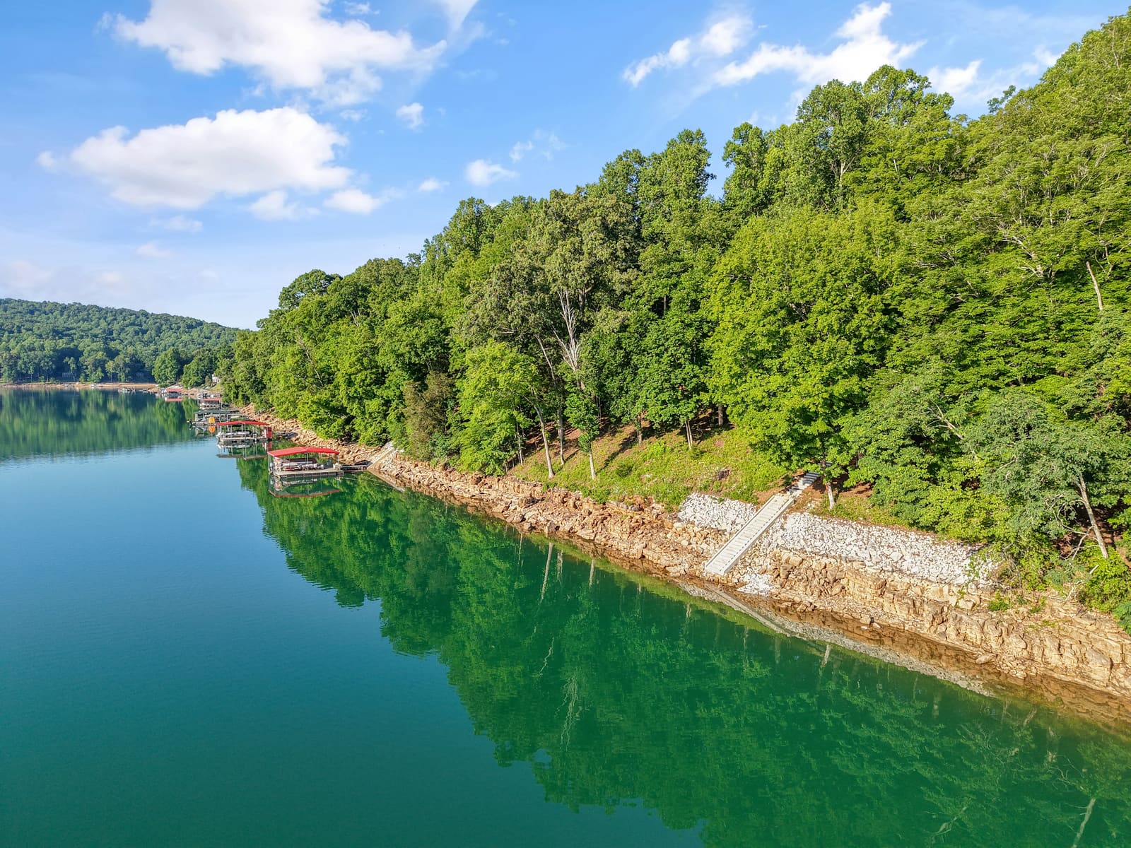 Aerial drone photo of a wooded lake shoreline with a private dock