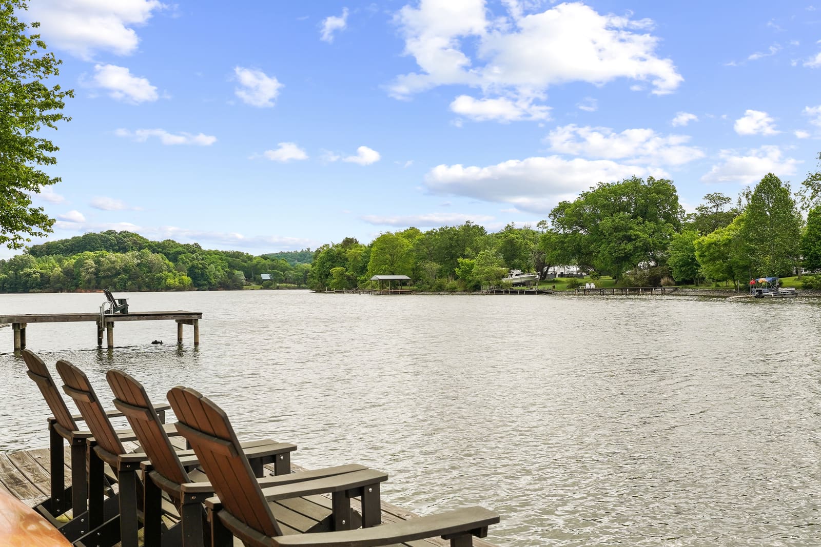 Lakefront shoreline with Adirondack chairs and a private dock at the water